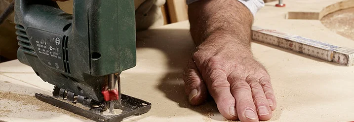 Person sägt mit Stichsäge Sperrholz